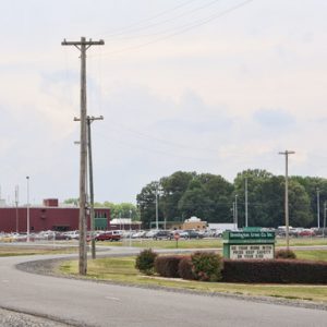 Paved curved road with power lines and factory building and sign