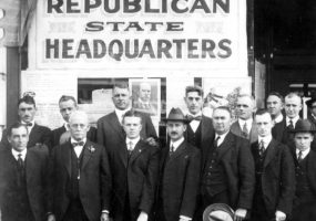 Group of white men in suits posing in front of building with "Republican State Headquarters" written on it