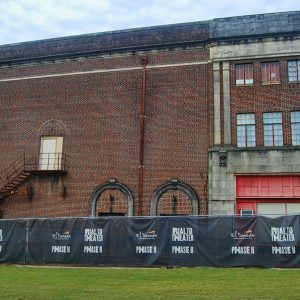 Side entrance on brick theater building with stairway and fence