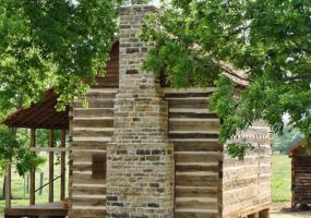 wood cabin with brick chimney and covered porch