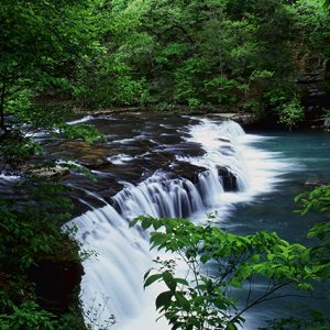 River with natural spill way and green foliage