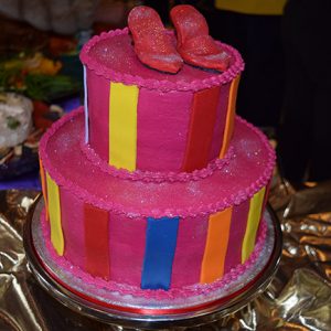 Red shoes on two-tiered cake with multicolored stripes