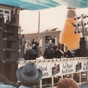 African-American man playing guitar on stage with mixed band