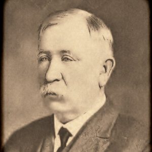 White man with white mustache in suit and tie