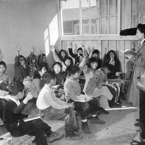 Japanese-American students and teacher in classroom with only simple benches