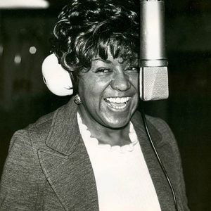 African-American woman smiling and singing into microphone