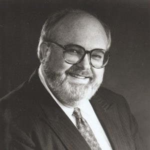 Bearded white man with glasses smiling in suit and tie