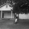 School building with slide swing set and tree in front yard