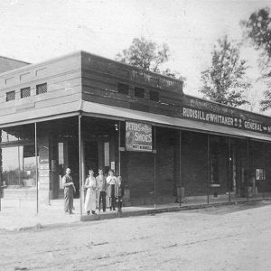 Group of people standing on sidewalk before storefront