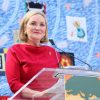 White woman in red dress speaking at a lectern