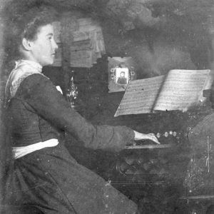 Young white woman in a dress playing an organ