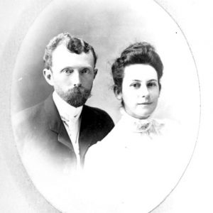 White man with a mustache in suit and woman in white dress