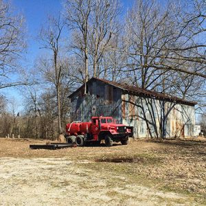 Red truck parked outside gin building under bald trees