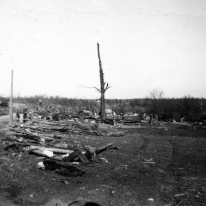 People and car parked in debris covered field with bald trees