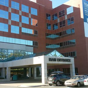 Multiple-story brick hospital building with covered entrance and parking lot