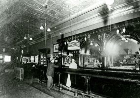 Bar tender and patron standing at saloon bar