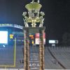 Close-up of trophy on grass in football stadium with goal scoreboard and stands in the background