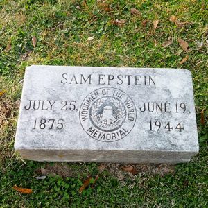 Flat grave stone on grass with inscription and "Woodsmen of the World Memorial" seal