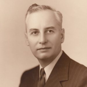 White man smiling in suit and tie