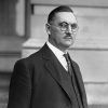 White man with glasses and mustache in suit and tie