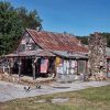 Storefront building with rusted metal roof stone chimney and covered porch on parking lot