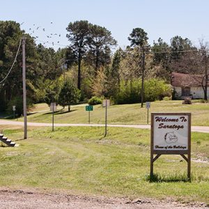 Mobile home with sign and street with house and trees in the background