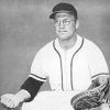 White man wearing baseball uniform squatting on grass