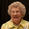 smiling older white woman with glasses in yellow floral shirt