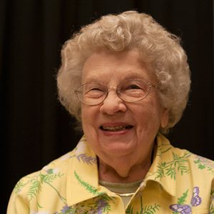 smiling older white woman with glasses in yellow floral shirt