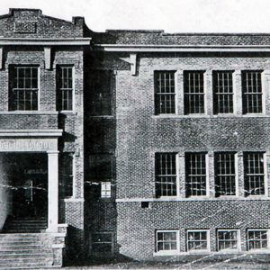 Three-story brick school building with rectangular windows