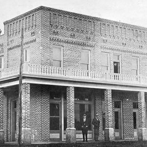 Two-story brick hotel building with two white men in uniform