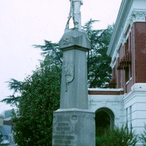 statue of soldier with gun on top of "C.S.A." monument next to brick building on street corner