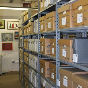 Interior of archives with framed artwork on the walls and materials in boxed on multiple shelves