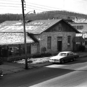 Stone building decorated with star decals snow on roof and shops parked cars coke machine