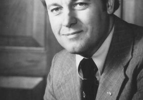 White man smiling in suit and tie