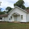 Single-story church building with covered entrance on grass