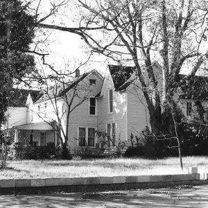 Two story white wooden house with trees outside