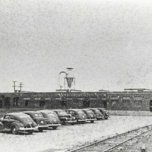 Cars parked outside flat roofed single-story building with water tower