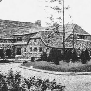 ornate stone building with arched entrances and driveway with trees