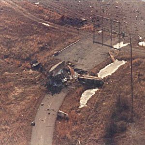 Debris on two-lane road behind gate as seen from above