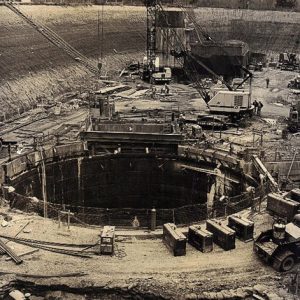 Massive circular hole in the earth surrounded by cranes and other items of construction equipment