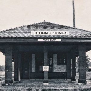 Front view of single-story brick train depot building labeled "Siloam Springs Museum"