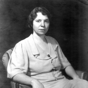 White woman with curly hair posing in a striped chair