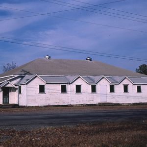 Single-story building with wood siding and hip roof on street