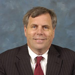 White man in black suit and red tie