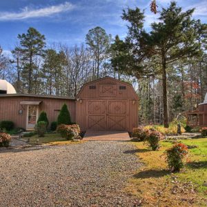 Single-story building and taller barn with observatory dome surrounded by fall foliage