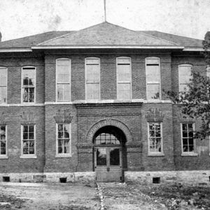 Two-story building with arched entrance and trees