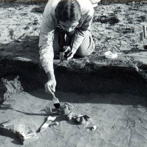 White man with brush working on dig site