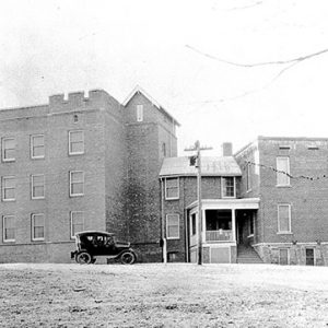 Multistory hospital building with smaller wing and car parked in front