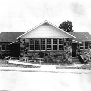 Stone building with parking lot and sidewalk with railing